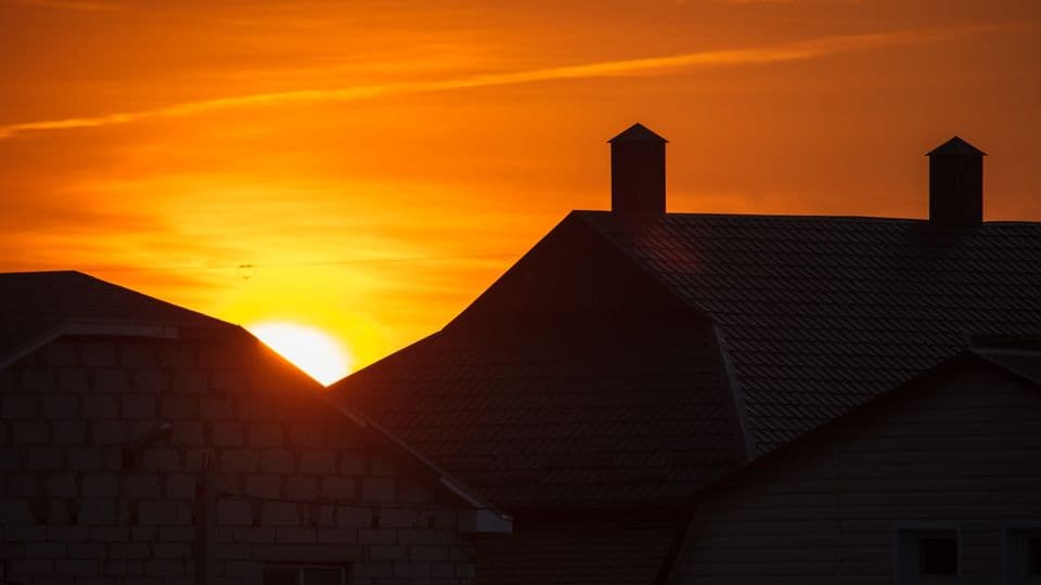 Silhouette of the roof of the house at sunset .
