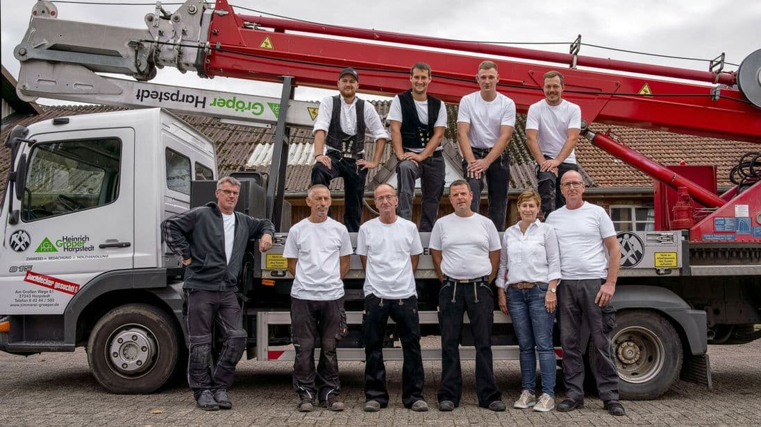 Familie Gröper zusammen mit dem Team der Zimmerei vor einem Lkw mit Kran.
