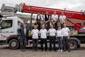Familie Gröper zusammen mit dem Team der Zimmerei vor einem Lkw mit Kran.