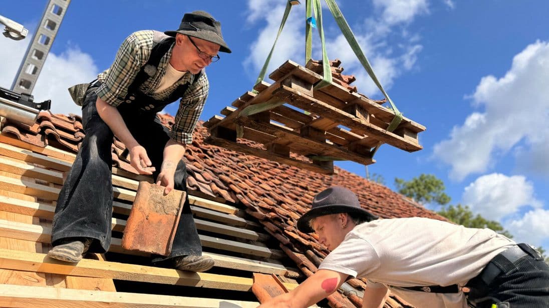 Hier verlegen Azubi und Meister die alten Ziegel wieder fachgerecht auf dem Dach des denkmalgeschützten Hauses.