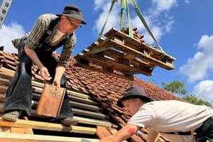 Hier verlegen Azubi und Meister die alten Ziegel wieder fachgerecht auf dem Dach des denkmalgeschützten Hauses.