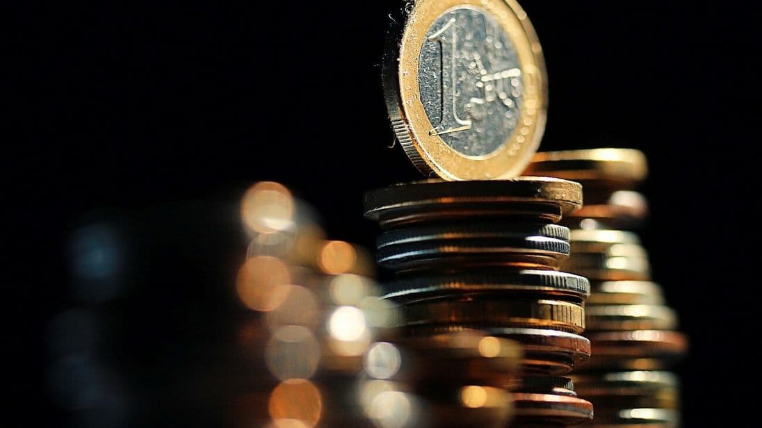 Eine funkelnde 1-Euro-Münze thront auf einem Münzstapel.