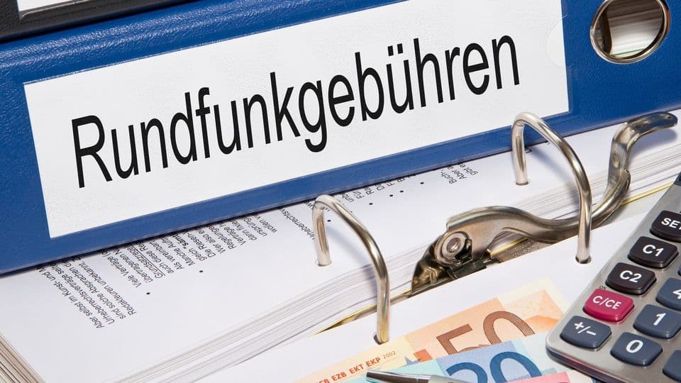 Rundfunkgebühren Ordner liegt auf dem Tisch mit Geldscheinen, Stift und Rechner