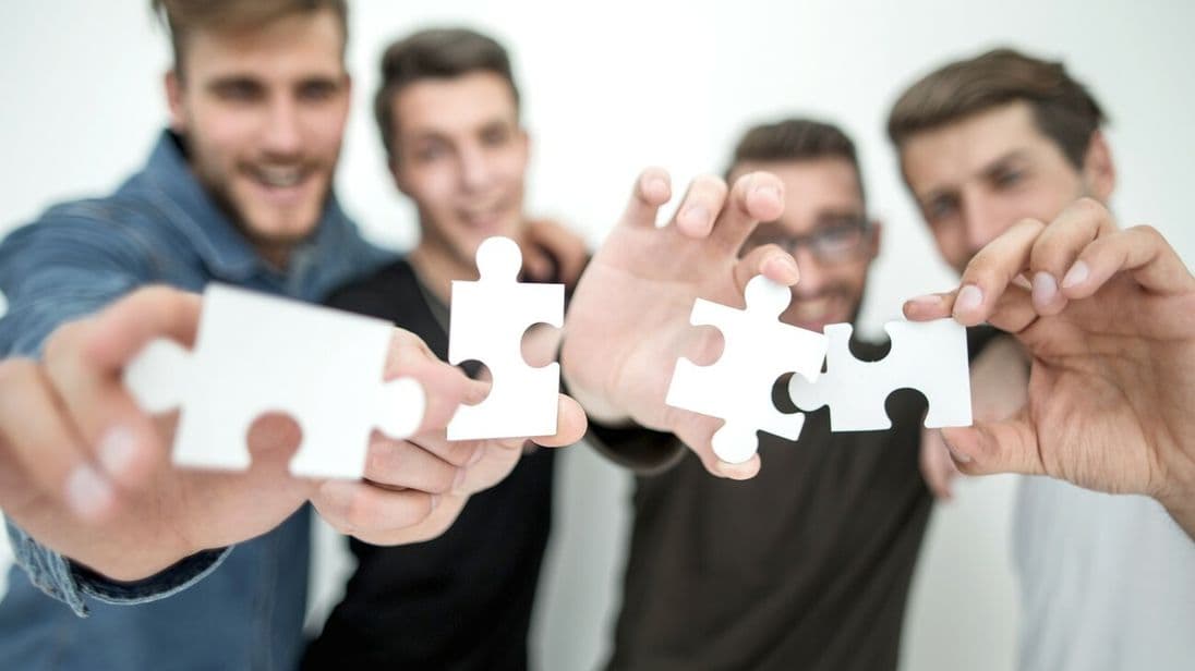 group of young people with puzzle pieces.the concept of solving the problem
