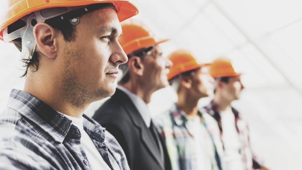 Bauarbeiter in einer Reihe
Close up. Standing Industrial Engineers in Shirts and Orange Helmets. Modern Construction and Engineering Concepts. Safety of Work in Production and Construction. Hard Work on Project.