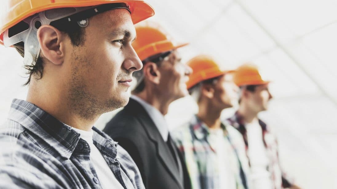 Bauarbeiter in einer Reihe
Close up. Standing Industrial Engineers in Shirts and Orange Helmets. Modern Construction and Engineering Concepts. Safety of Work in Production and Construction. Hard Work on Project.