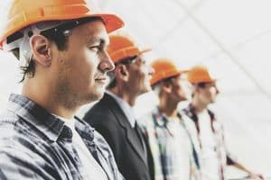 Bauarbeiter in einer Reihe
Close up. Standing Industrial Engineers in Shirts and Orange Helmets. Modern Construction and Engineering Concepts. Safety of Work in Production and Construction. Hard Work on Project.