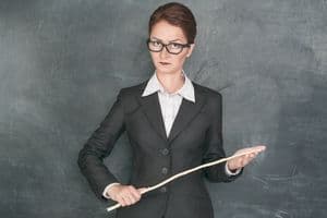 Strict teacher with wooden stick looking at someone