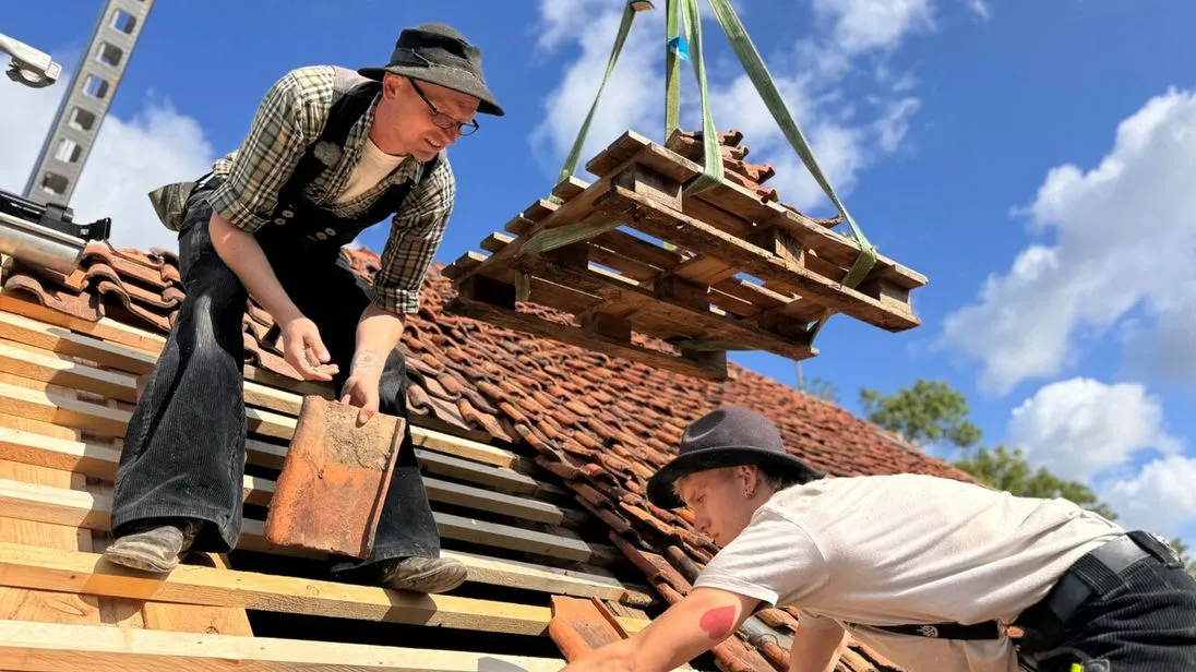 Hier verlegen Azubi und Meister die alten Ziegel wieder fachgerecht auf dem Dach des denkmalgeschützten Hauses.